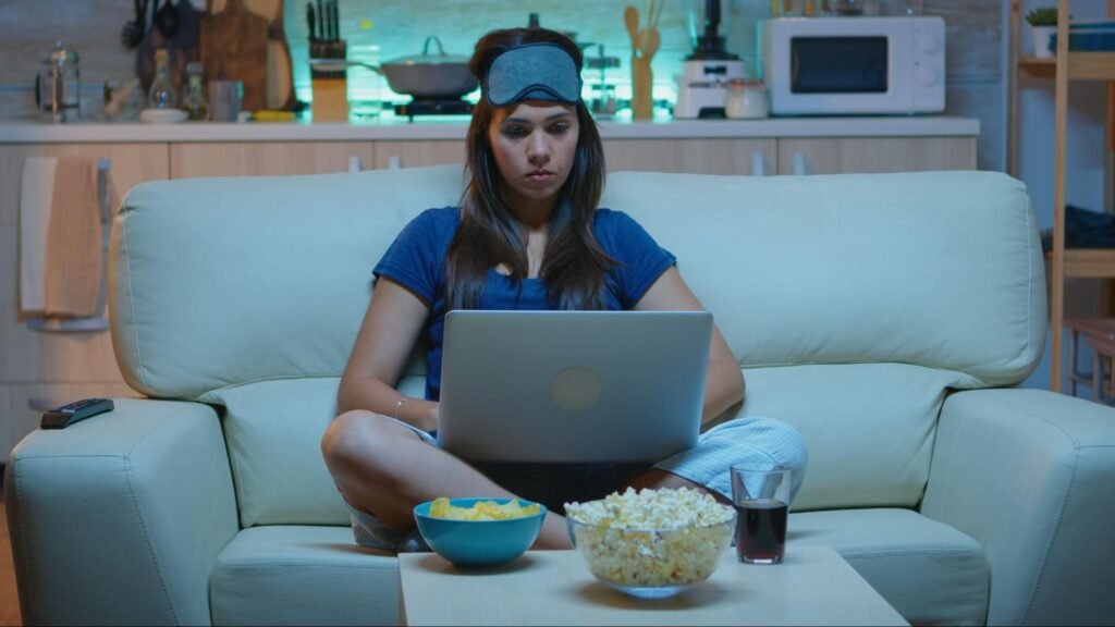 Woman in pajamas using a laptop on the couch at night